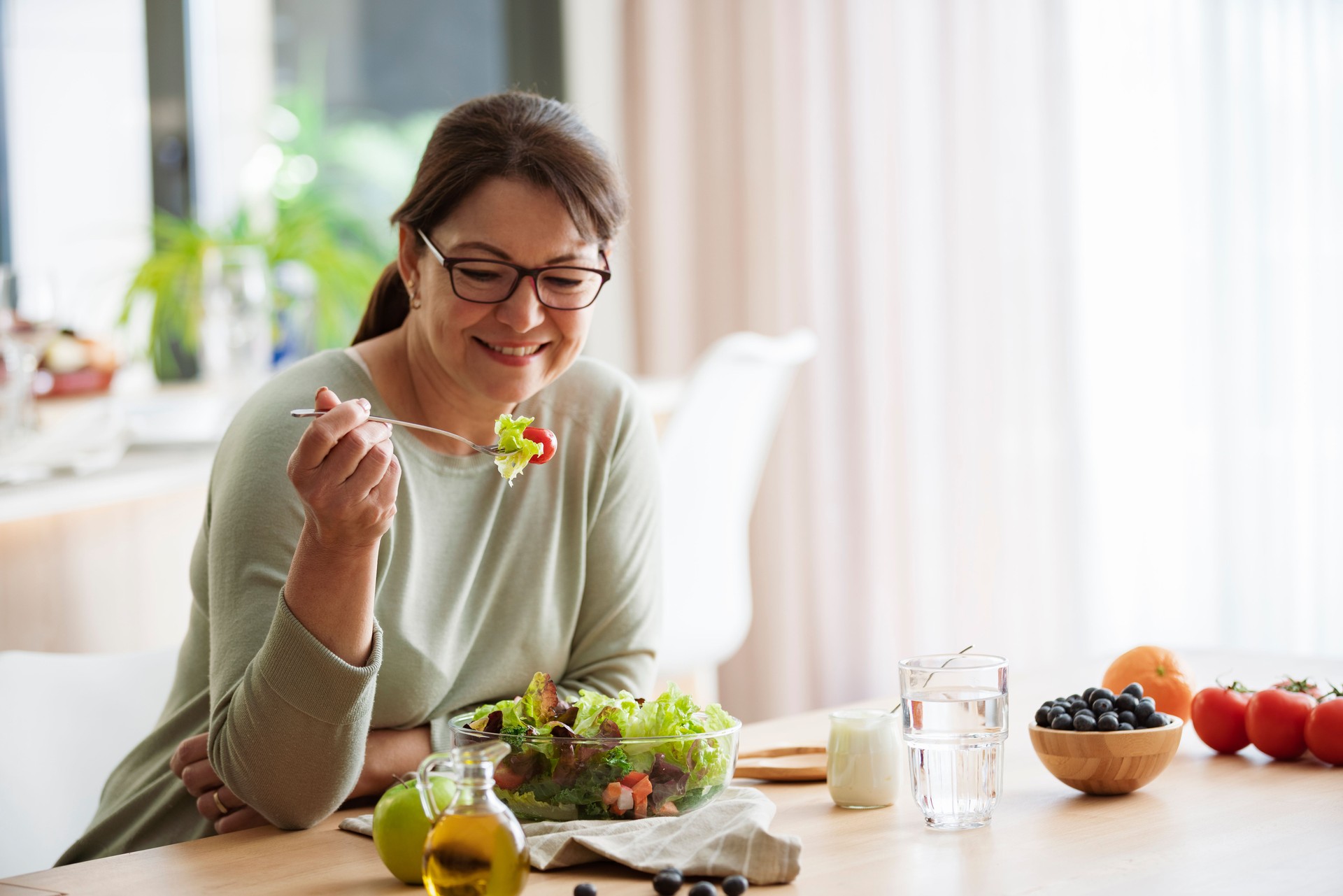 Woman eating freshly prepared lettuce salad at home. Healhy eating and dieting concept